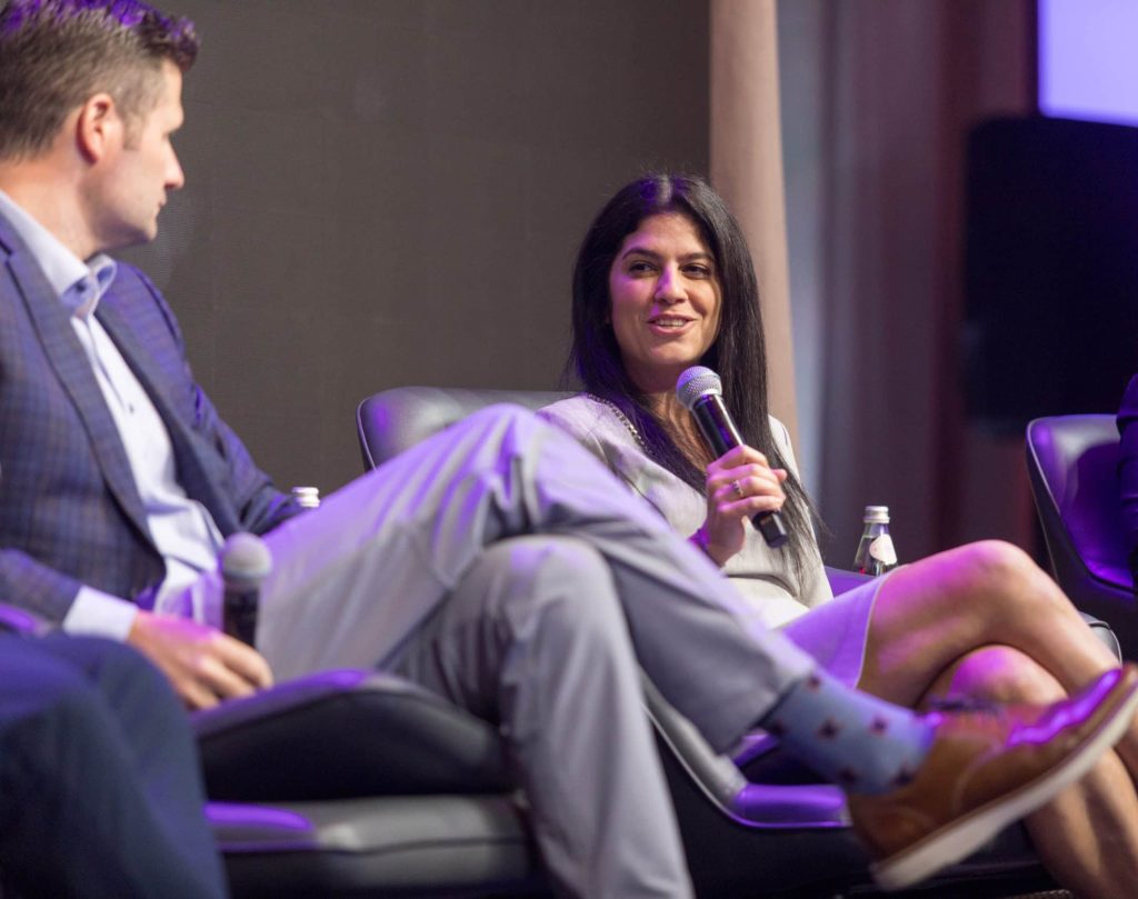 Panel discussion at a conference, featuring a woman speaking passionately into a microphone.