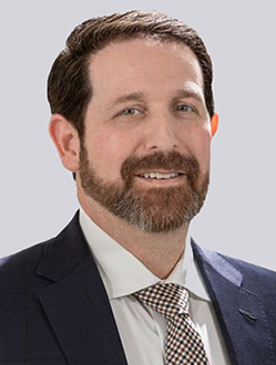 Man in suit with beard smiling.